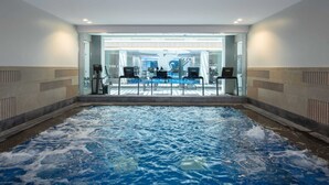 Ein Innenpool mit Blick auf einen Spa-Bereich und Fitnessgeräte.