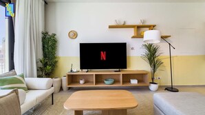 Ein modernes Wohnzimmer mit Flachbildfernseher, Holzmöbeln und Dekorationselementen.