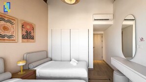 Ein Hotelzimmer mit zwei Betten, einem Nachttisch mit Lampe, einem großen Spiegel und Bildern an der Wand.