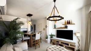 A modern living room with a sofa, ottoman, TV, and a dining area with chairs and a table. - Genial 2bdr @ Swan Lake El Gouna (El Gouna)