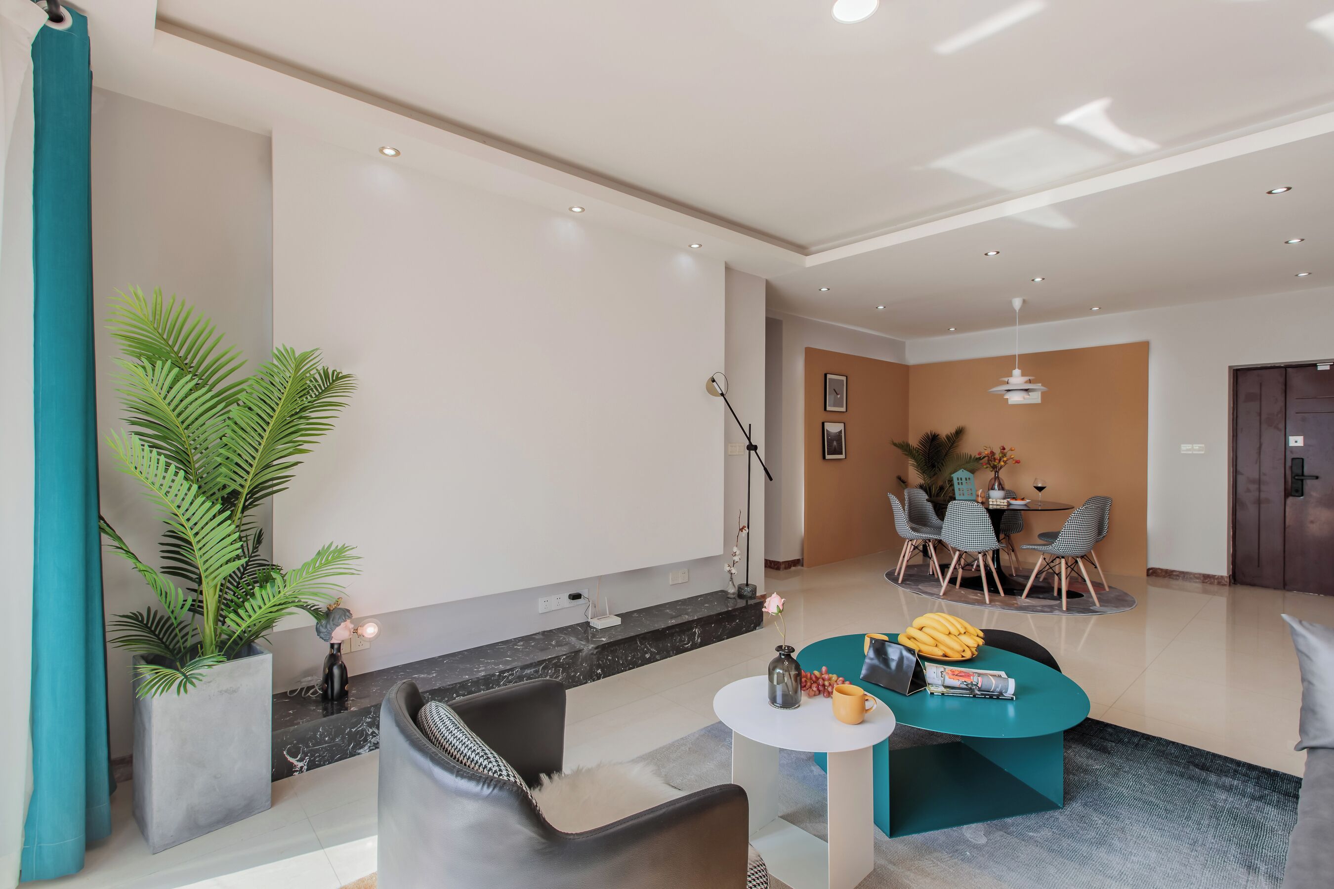 A modern living room with a sofa, coffee table, and a dining area with chairs and a table.