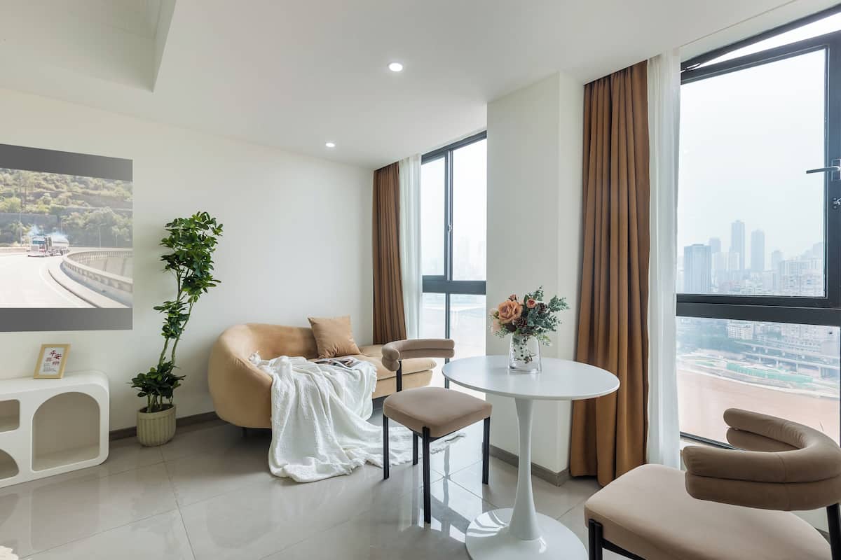 A modern living room with a sofa, two chairs, a small table, and a potted plant.