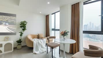 A modern living room with a sofa, two chairs, a small table, and a potted plant.