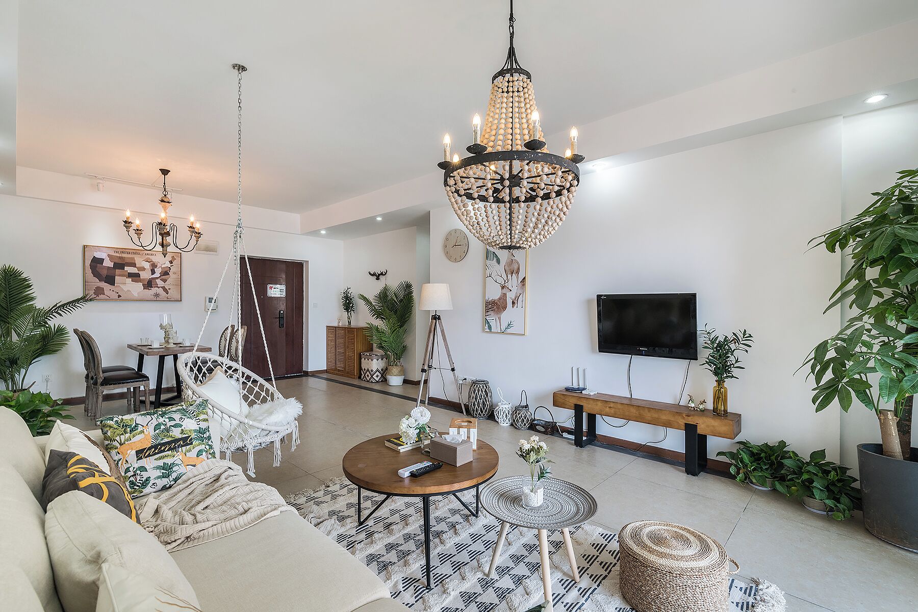 A spacious living room with a chandelier, a television, and various seating arrangements including a sofa and chairs.