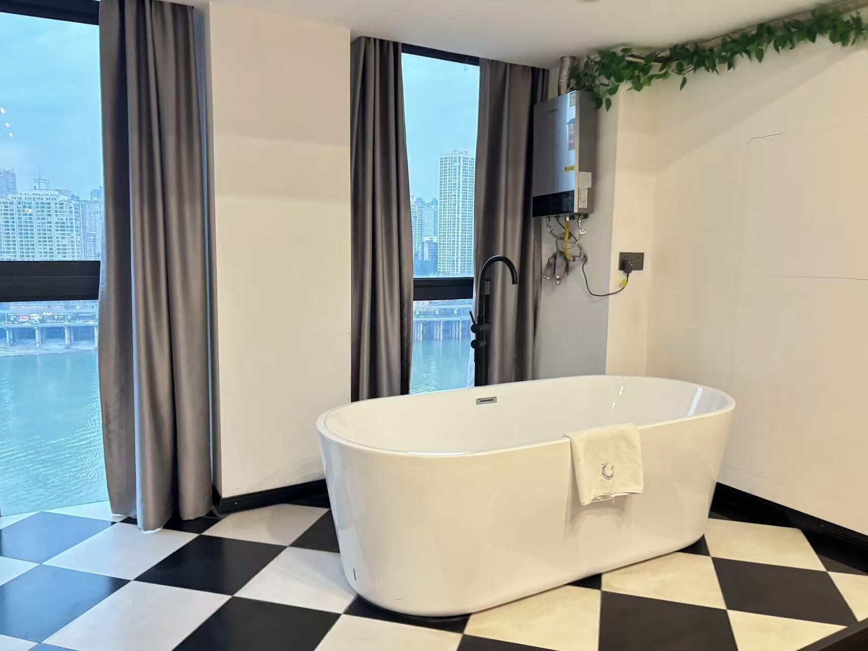 Ein modernes Badezimmer mit freistehender Badewanne, großen Fenstern mit Vorhängen und einem Schachbrettboden.