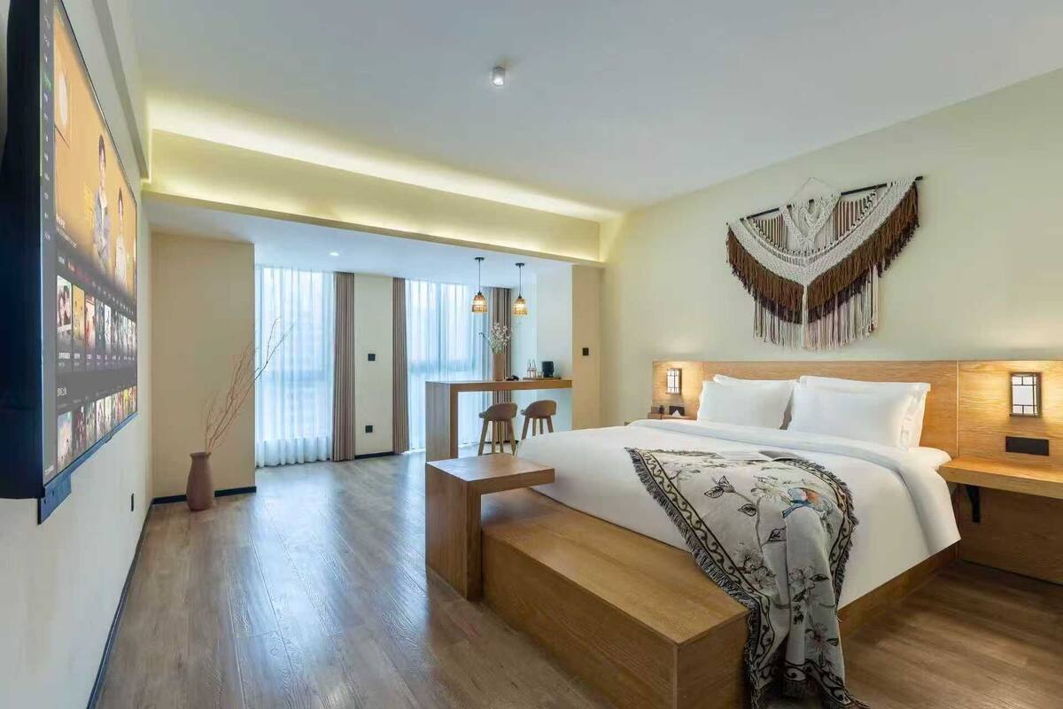 A modern hotel room with a large bed, a desk, and a seating area.