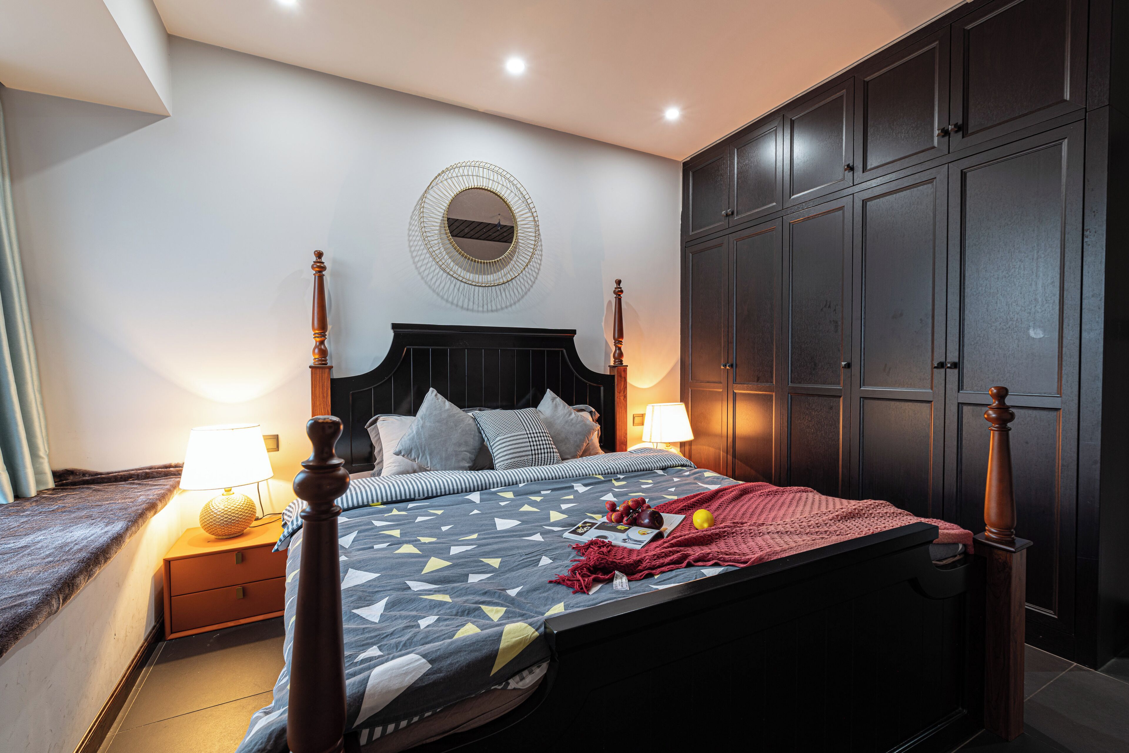 Une chambre à coucher comprenant un lit, des lampes de chevet, une tête de lit, une armoire et un miroir fixé au mur.