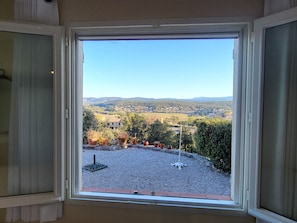 A room with a large window overlooking a rural landscape with houses and greenery.
