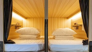 Habitación con espejo, dos camas, paredes de madera y una estantería con libros.