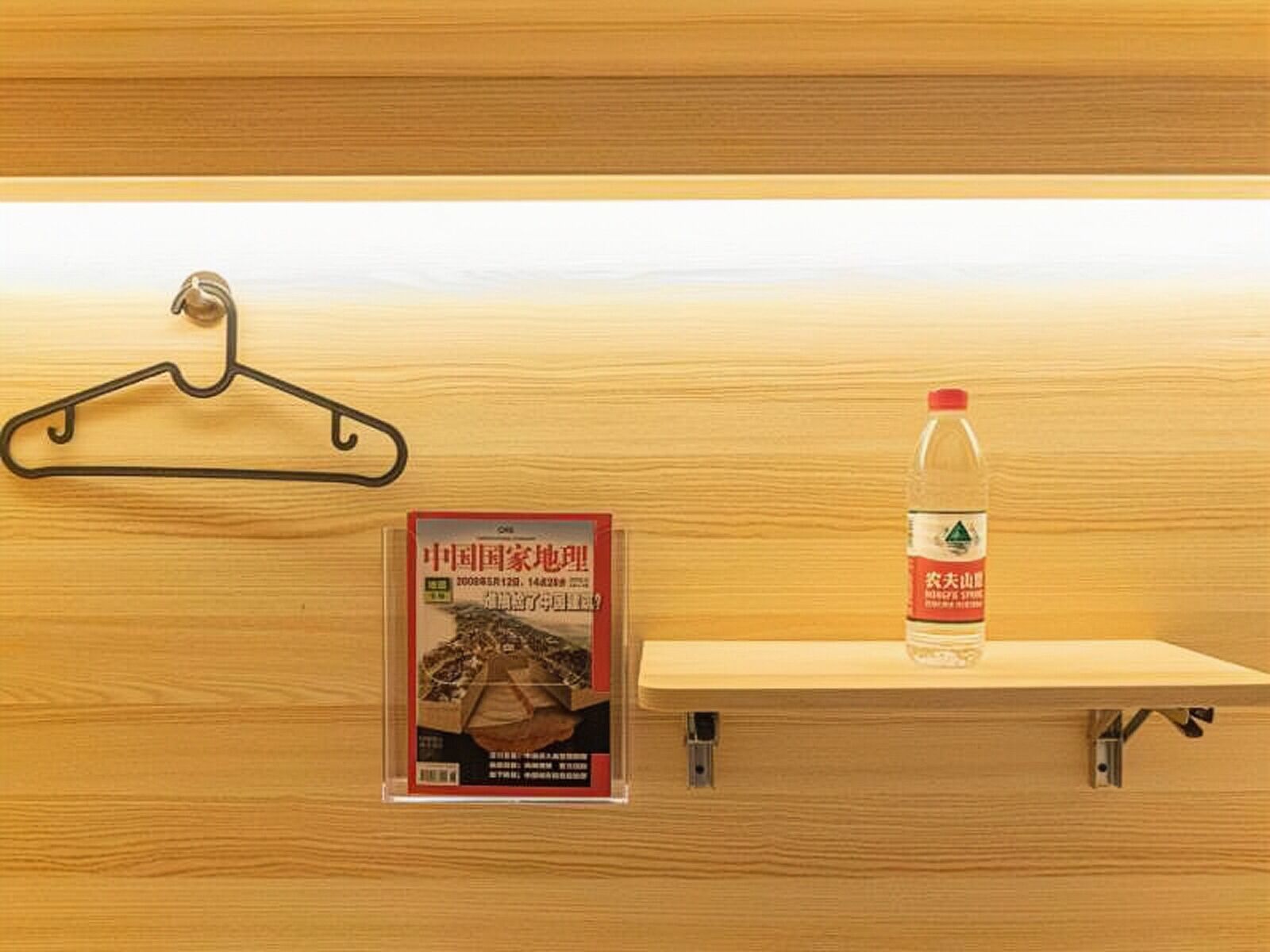 Una pared de madera con un perchero negro y una botella de plástico en un estante.