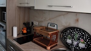 A kitchen with a countertop, a black cutting board, a wooden basket, and a black plate with heart patterns. - Modern Apartment In City Center (Tiranë)