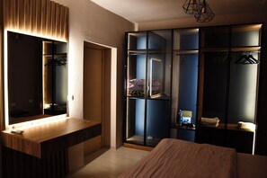 Quarto moderno com toucador de madeira, espelho grande, guarda-roupa com portas de vidro e luminária pendente.