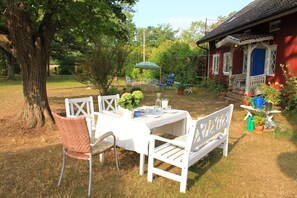 An outdoor dining area with a table set for four, surrounded by white chairs. - Öland's most beautiful vacation farm (Kalmar)