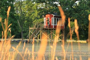 A red cabin with a wooden deck and stairs, surrounded by trees. - Öland's most beautiful vacation farm (Kalmar)
