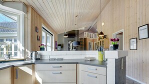 Eine moderne Küche mit Holzschränken, einer schwarzen Arbeitsplatte und einem großen Fenster.