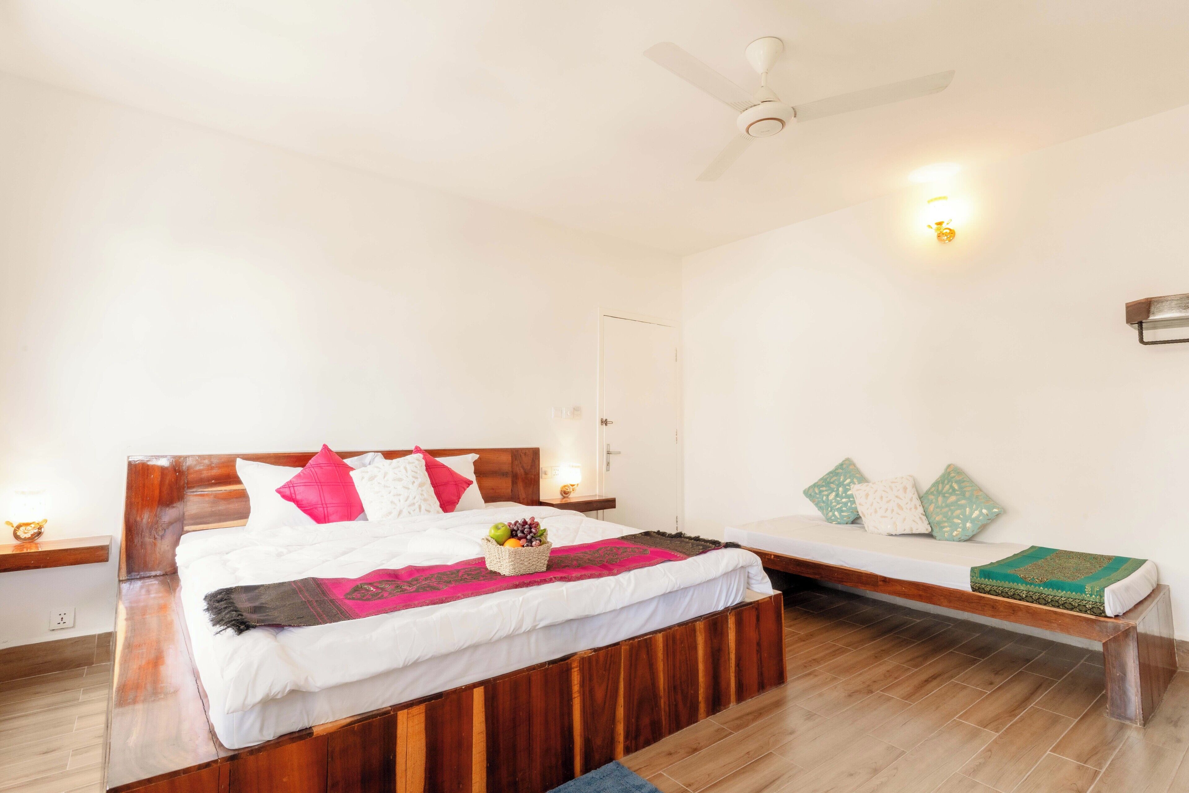 A bedroom with a wooden bed, a bedside table, a bench, and a ceiling fan.