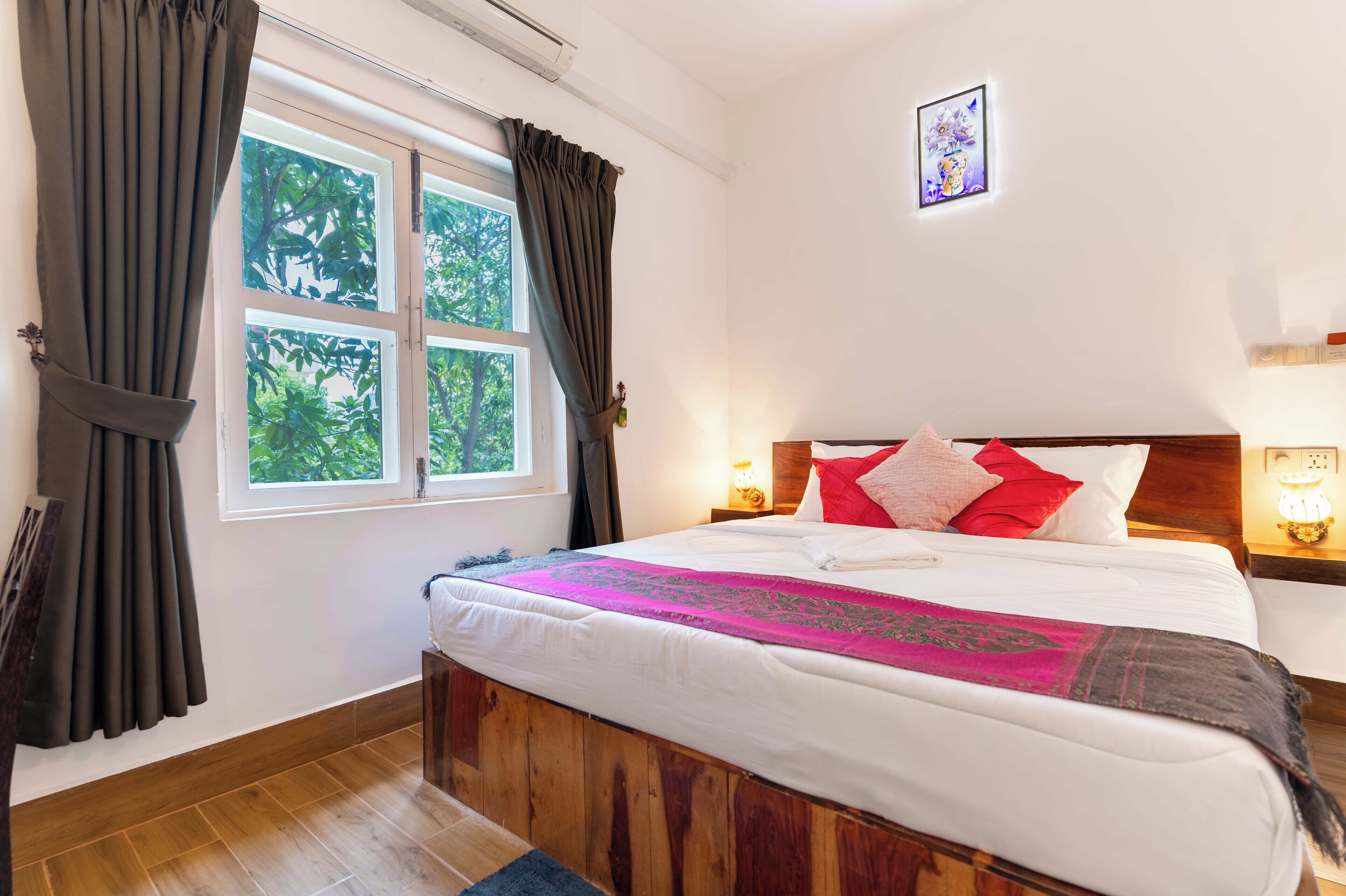Een slaapkamer met een houten bed, wit beddengoed, een roze decoratief plaid en een raam met gordijnen.