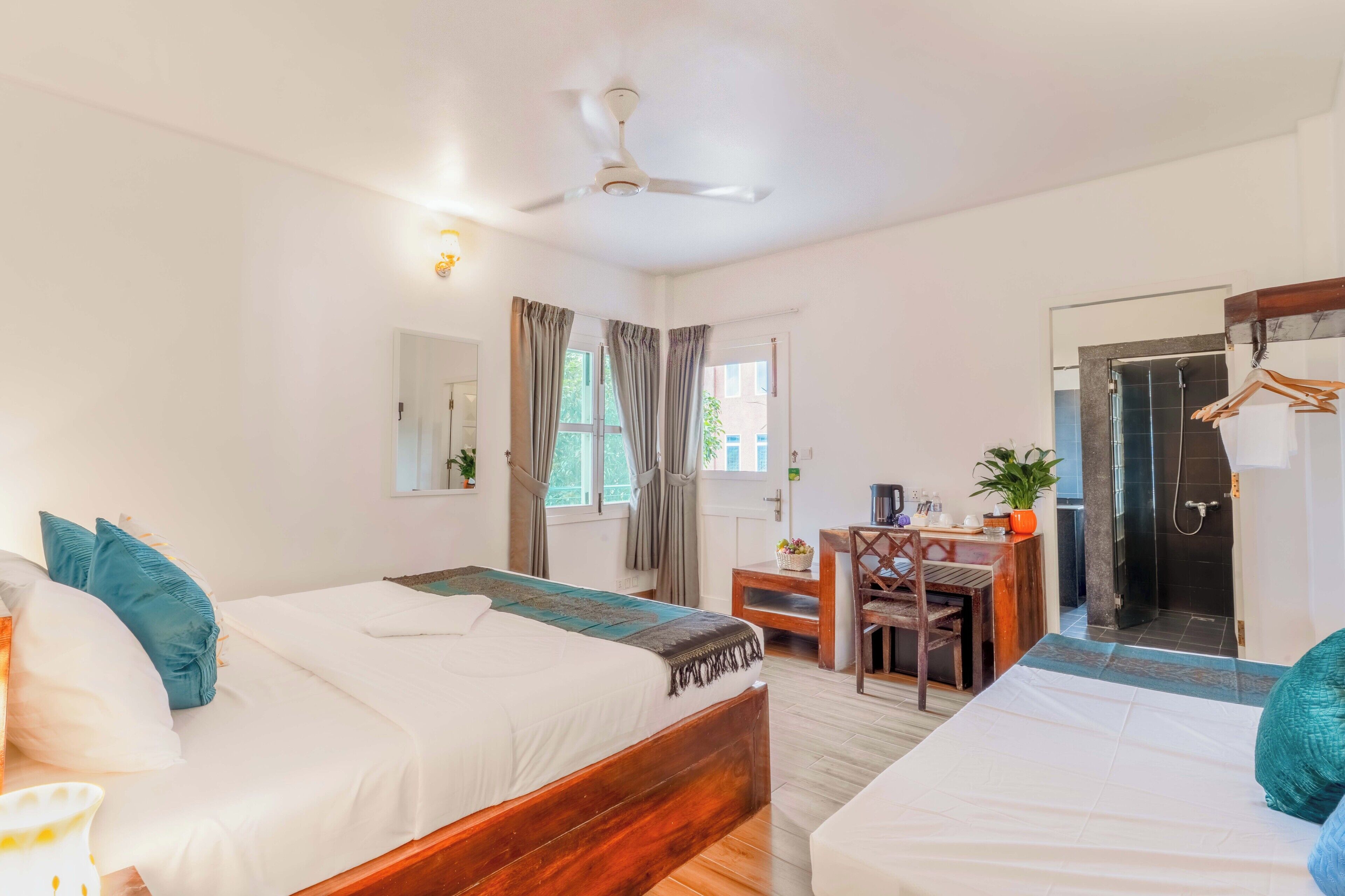 A hotel room with two beds, a desk, a chair, a shower, and a mirror.
