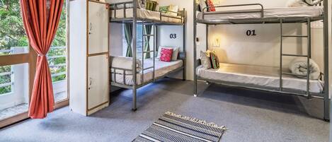 A dormitory room with bunk beds numbered 01 to 04, a wardrobe, and a window with curtains.