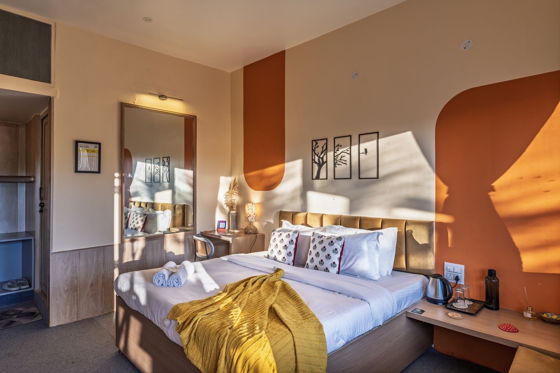 A hotel room with a bed, bedside table, and a mirror.