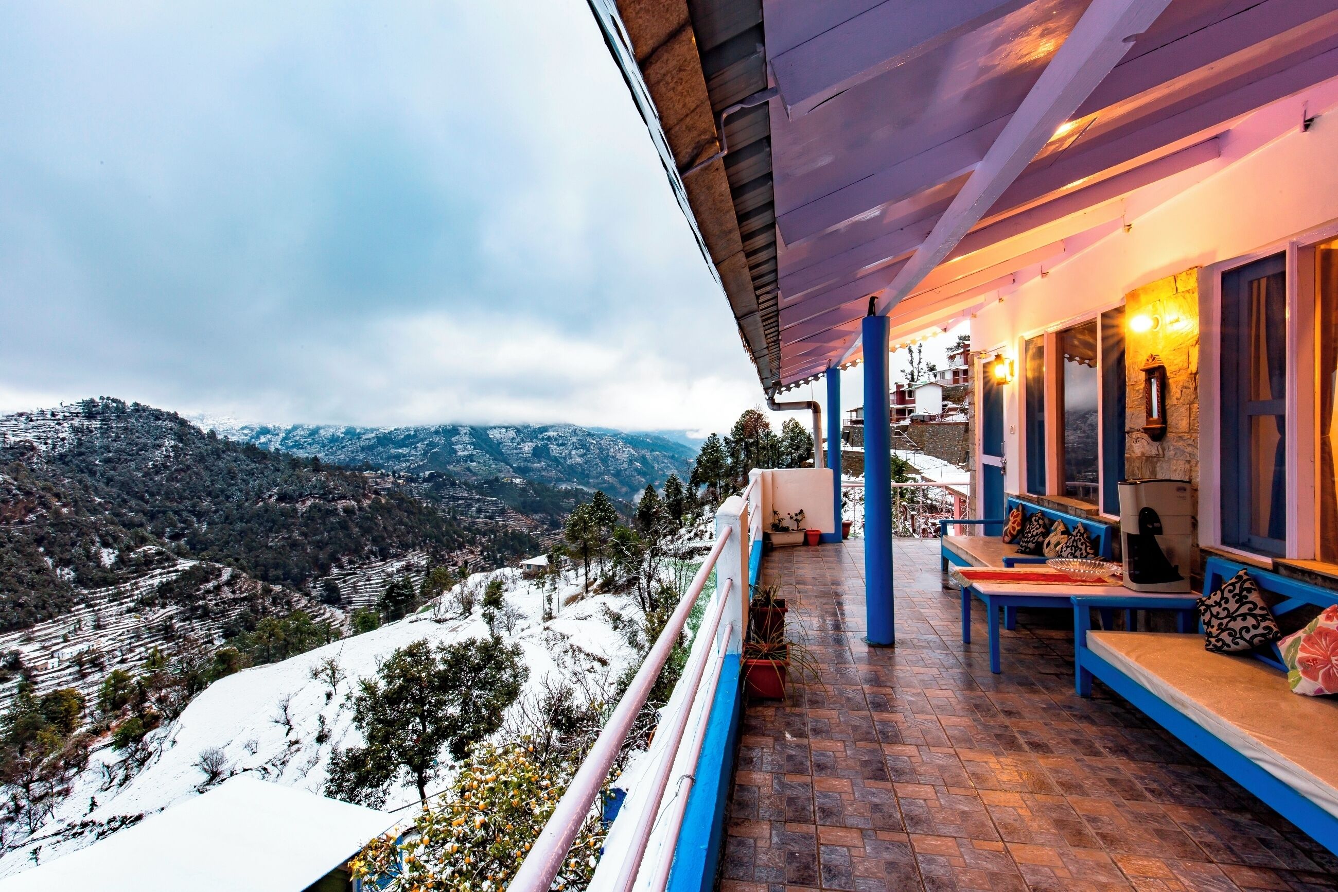 Varanda com vista para colinas cobertas de neve e restaurante com mesas ao ar livre.