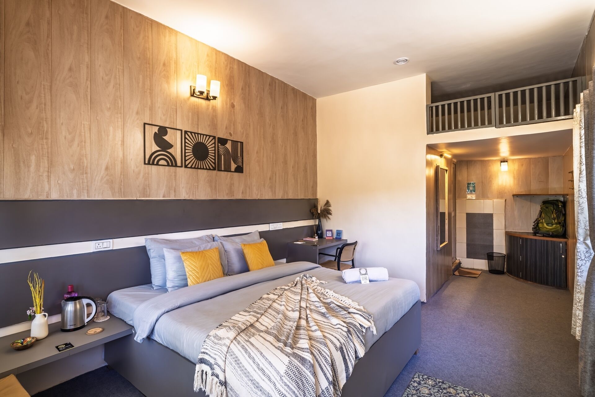 A modern bedroom with a large bed, bedside tables, a desk, and a view of the living area.