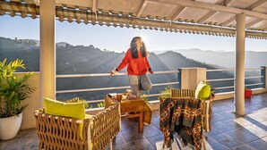 A covered outdoor seating area with a view of hills. - PACK Mukteshwar (Kosiyakutoli)