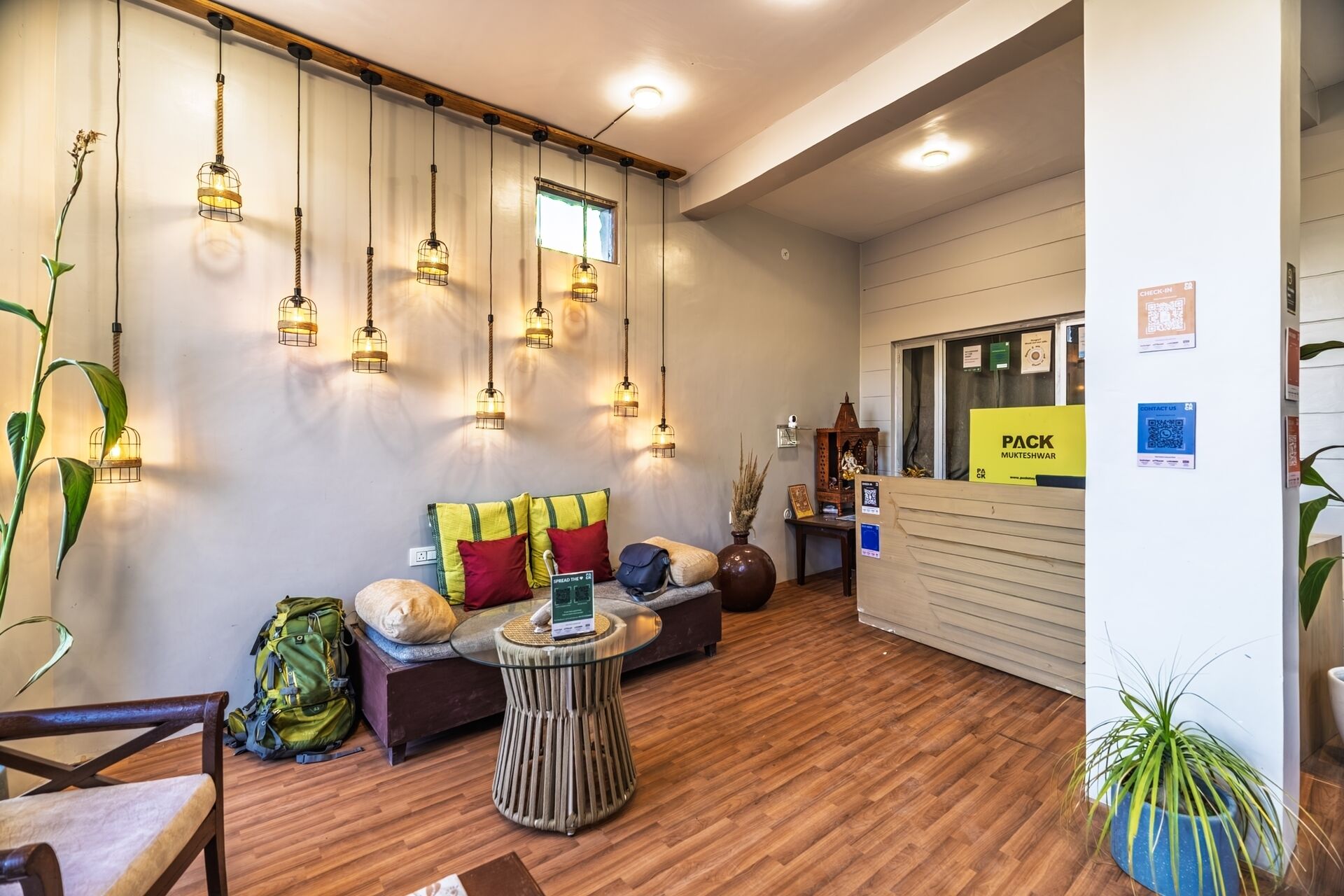 A hotel lobby with wooden flooring, a reception desk, and multiple hanging light fixtures.