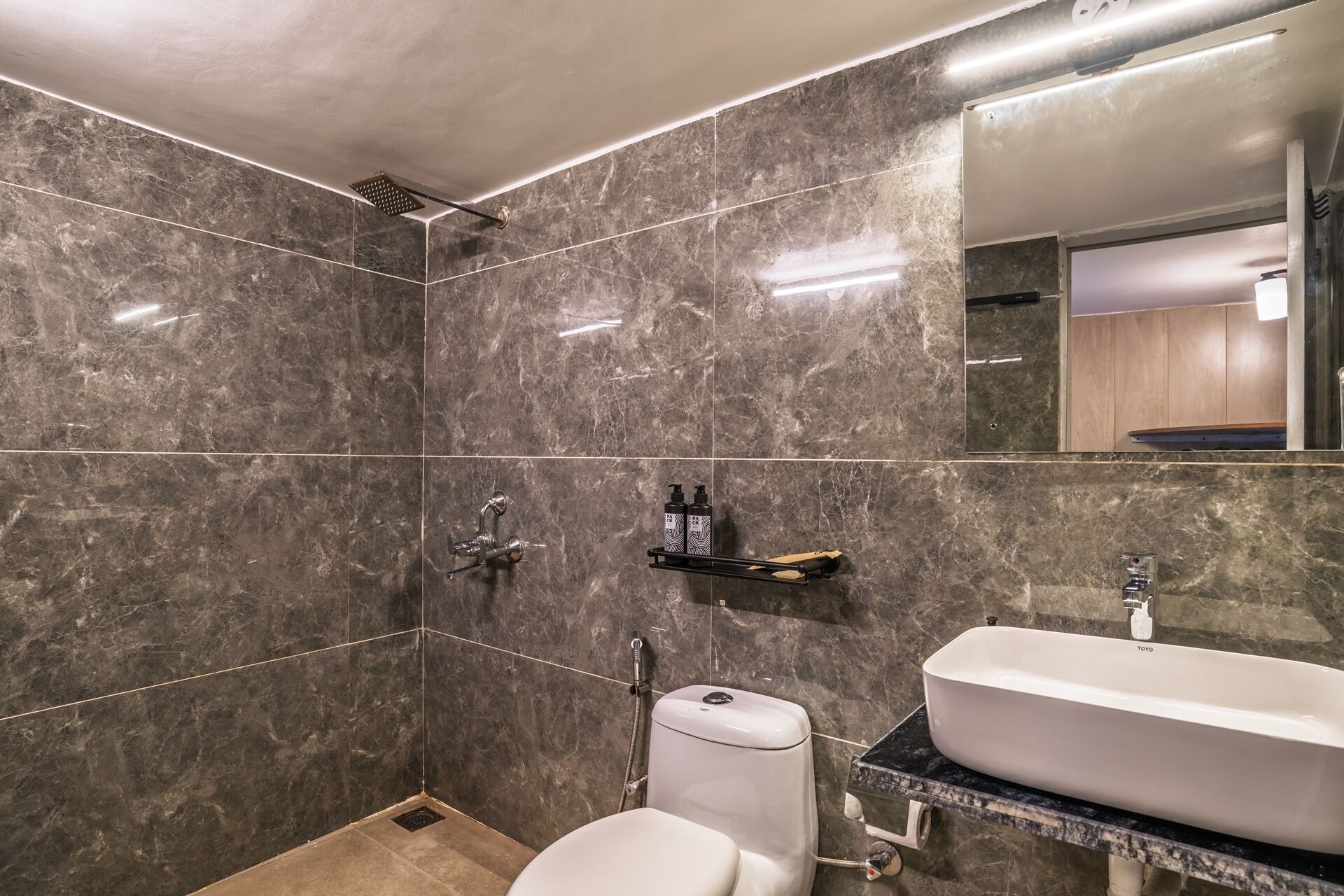 A modern bathroom with a large mirror, a white sink, and a shower area.