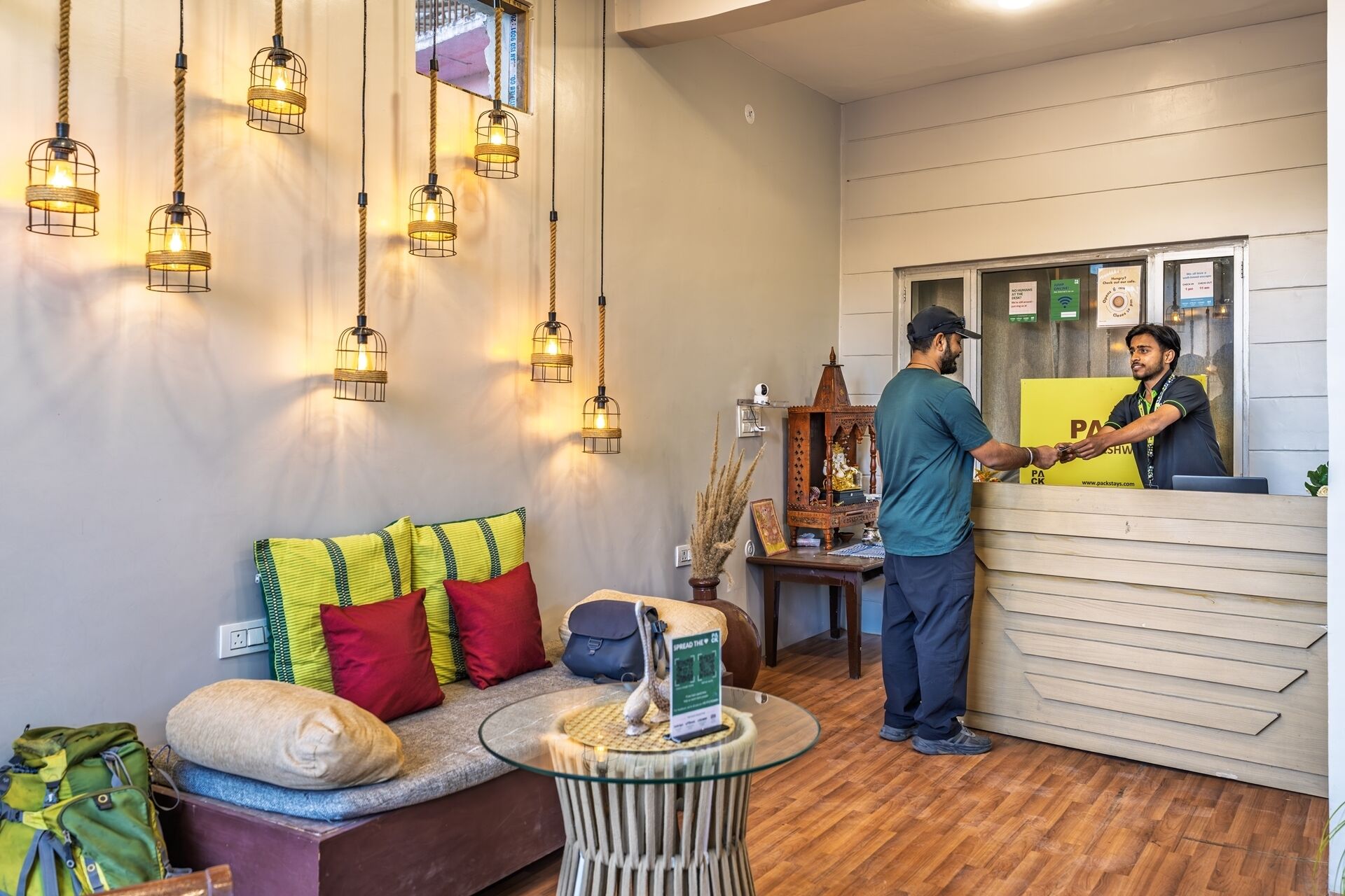 A reception area with a wooden reception desk, a sofa with colorful cushions, and hanging light fixtures.