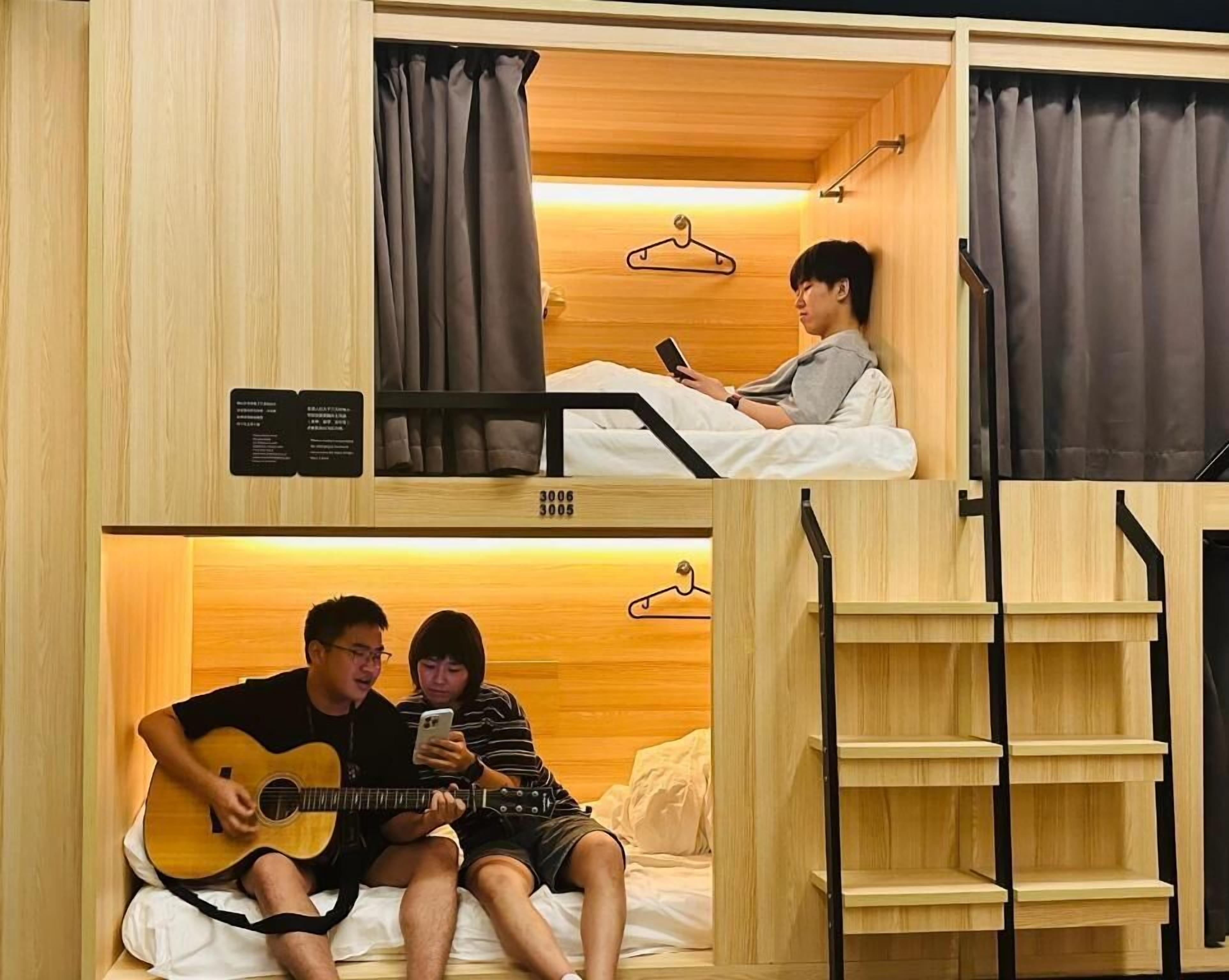 A compact hotel room with bunk beds, wooden walls, and a simple layout.