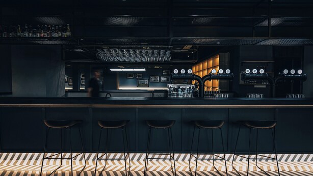A bar area with a counter, stools, and a patterned floor.