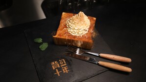 A dessert on a slate serving board with chopsticks and a fork beside it.