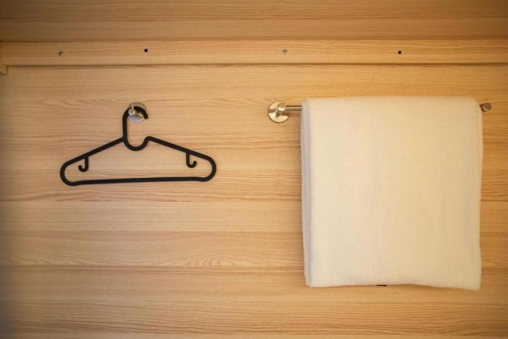 Una puerta de madera con un perchero negro y una toalla blanca colgada en un toallero.