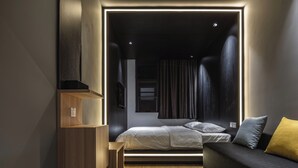 A modern bedroom with a bed, a sofa, and a built-in shelf unit.