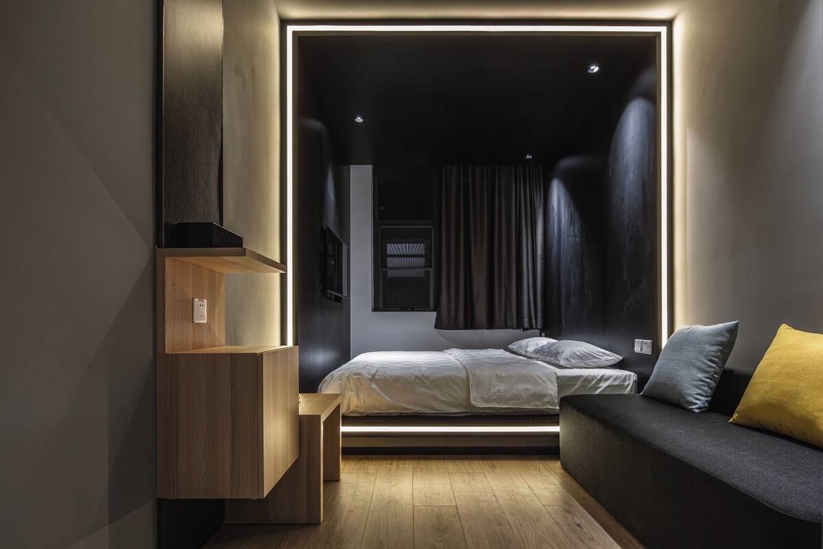 Ein modernes Schlafzimmer mit einem Bett, einer Couch und einer eingebauten Regaleinheit.