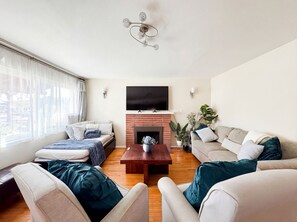 Una sala de estar moderna con chimenea, dos sofás, una mesa de centro y un televisor sobre la chimenea.