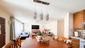 Una cocina moderna con armarios de madera, horno empotrado y un comedor con mesa y sillas de madera.