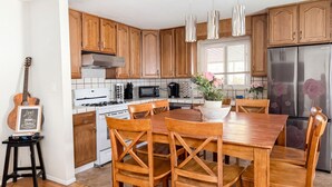Una cocina moderna con armarios de madera, electrodomésticos de acero inoxidable y un comedor con sillas de madera.