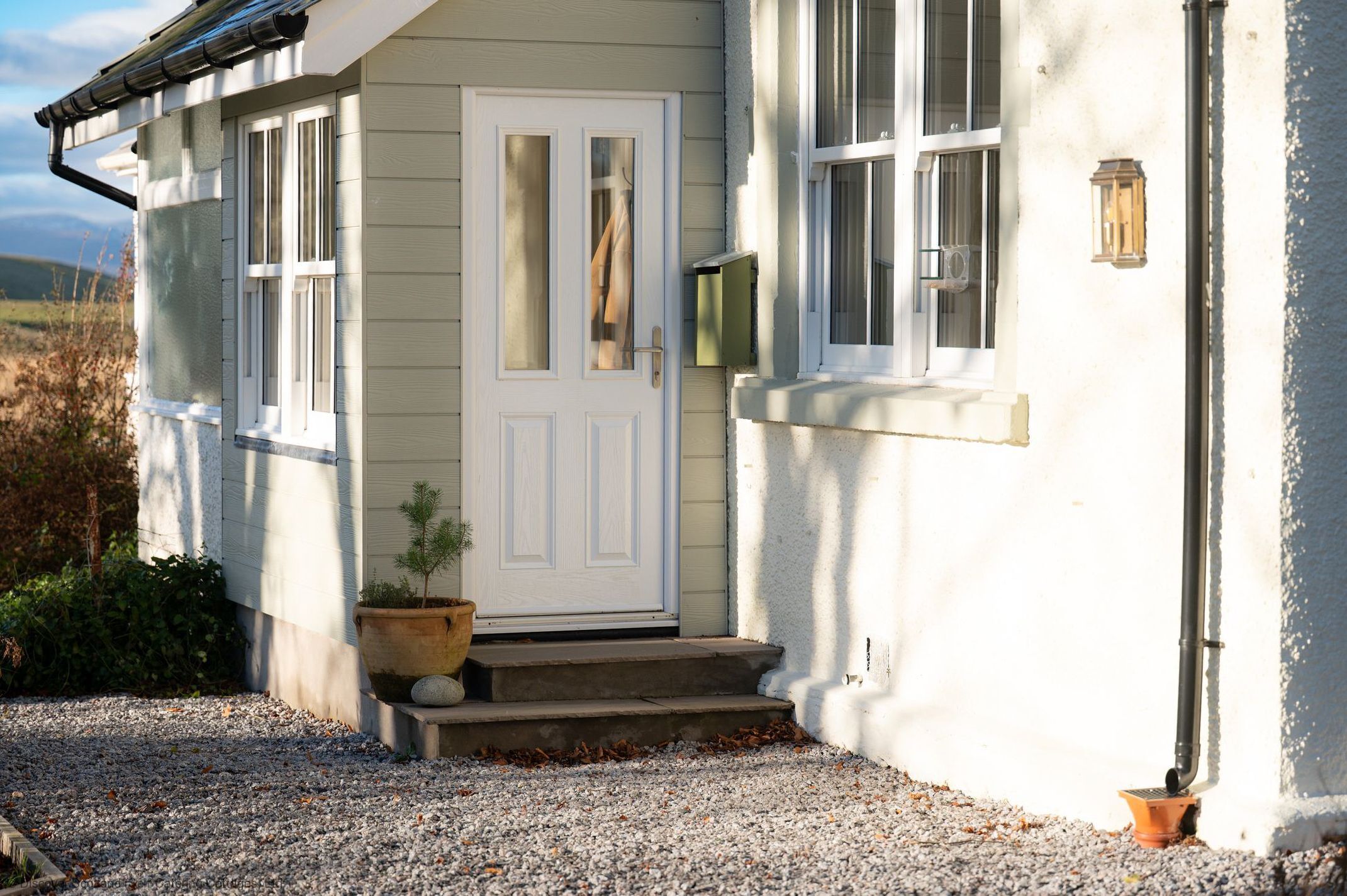 Una casa con una porta bianca, un piccolo portico e delle scale che conducono all'ingresso.