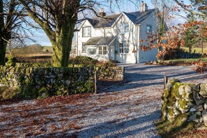 Une maison blanche avec un mur en pierre et une allée gravillonnée.