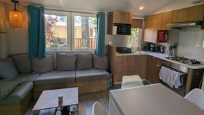 Un espace de vie compact comprenant un coin cuisine, un canapé, une table à manger et une vue sur l’extérieur.