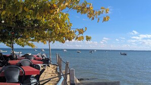 Un restaurant en bord de mer avec une terrasse, une vue sur l’océan et des bateaux visibles au loin.