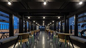 A long corridor with tables and chairs, large windows, and a view of the outside.