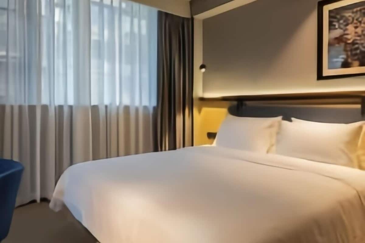 Een hotelkamer met een groot bed, een bureau en een raam met gordijnen.