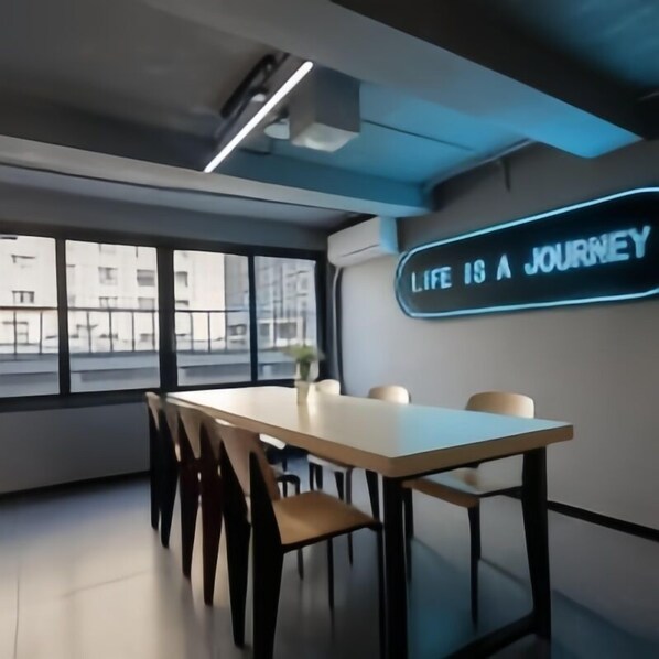 Uma sala de conferências moderna com uma mesa comprida, cadeiras e um letreiro de neon que diz 'Life is a JOURNEY'.