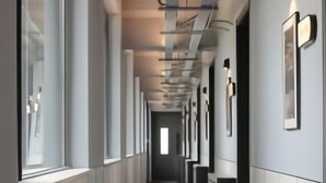 A long, narrow hallway with white walls and a dark floor.