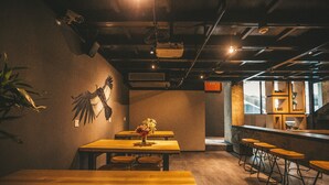 L’intérieur d’un restaurant, avec des tables en bois, des tabourets de bar et un élément décoratif mural.