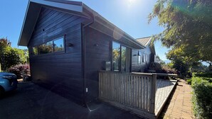 Una casa moderna con fachada oscura, una terraza de madera y un garaje.