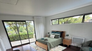 Un dormitorio moderno con una cama grande, un escritorio y una zona de comedor.